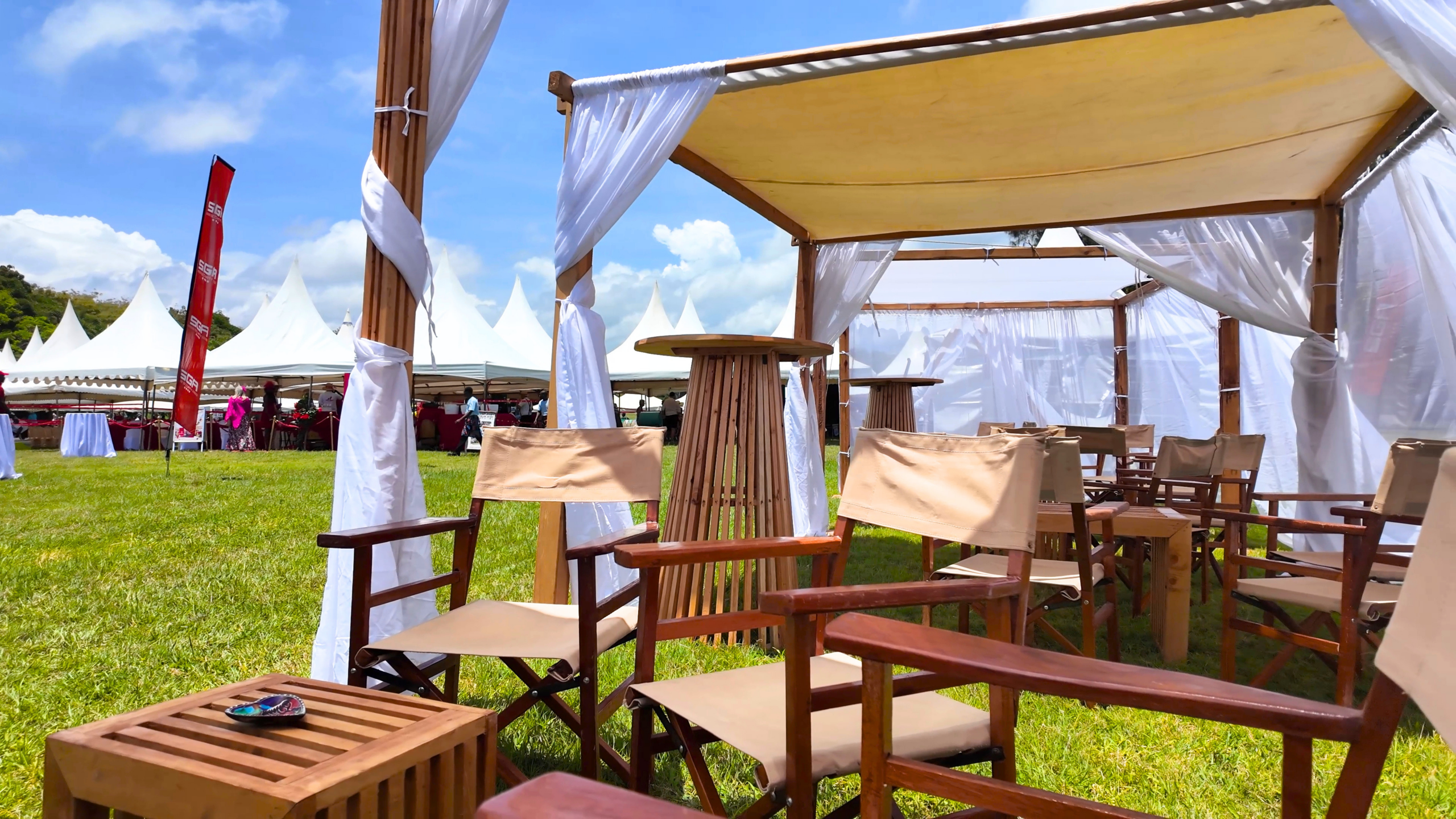 Wooden chairs and tables arranged beneath a shaded event canopy in Diani
